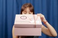 young brown-haired girl opens a pink box with a gift on a blue background Royalty Free Stock Photo