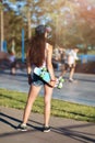 Young brown-haired woman with a skateboard in her hands on the background of a skateboarding platform