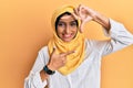 Young brunette arab woman wearing traditional islamic hijab scarf smiling making frame with hands and fingers with happy face Royalty Free Stock Photo