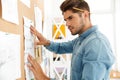 Young brunette architect working with drawing on wall board in office Royalty Free Stock Photo