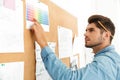 Young brunette architect working with drawing on wall board in office Royalty Free Stock Photo