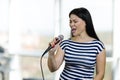 Young brunette asian woman is singing a song with microphone. Royalty Free Stock Photo