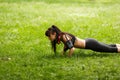 Young brunette athletic woman doing push ups on grass