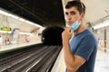 Young brunette boy in navy blue t-shirt lowering his mask in the subway