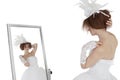 Young brunette bride in wedding gown looking at herself in mirror over white background Royalty Free Stock Photo