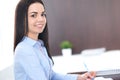 Young brunette business woman looks like a student girl working in office. Hispanic or latin american girl happy at work Royalty Free Stock Photo