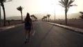 Young brunette caucasian girl jogging at tropical highway at sunrise