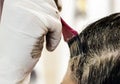 A young brunette caucasian woman dying her hair with a pink brush using white gloves at her home