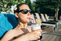 Young brunette cheerful woman suntanning near hotel swimming pool Royalty Free Stock Photo