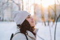 Young brunette curly-haired woman walk in winter on the street breathes frosty air with steam from her mouth. Side view