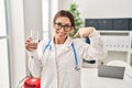 Young brunette doctor woman holding glass of water pointing finger to one self smiling happy and proud Royalty Free Stock Photo