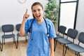 Young brunette doctor woman at waiting room pointing finger up with successful idea Royalty Free Stock Photo