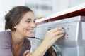 young brunette doing laundry in kitchen and smiling Royalty Free Stock Photo