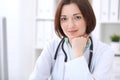 Young brunette female doctor sitting at a desk and working on the computer at the hospital office. Royalty Free Stock Photo