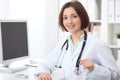 Young brunette female doctor sitting at a desk and working on the computer at the hospital office. Royalty Free Stock Photo