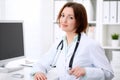 Young brunette female doctor sitting at a desk and working on the computer at the hospital office. Royalty Free Stock Photo