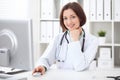 Young brunette female doctor sitting at a desk and working on the computer at the hospital office. Royalty Free Stock Photo