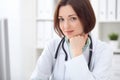 Young brunette female doctor sitting at a desk and working on the computer at the hospital office. Royalty Free Stock Photo