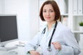 Young brunette female doctor sitting at the table and working with computer at hospital office Royalty Free Stock Photo