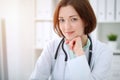 Young brunette female doctor sitting at the table and working with computer at hospital office Royalty Free Stock Photo