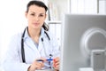 Young brunette female doctor sitting at the table and working by computer at hospital office. Royalty Free Stock Photo