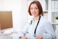 Young brunette female doctor sitting at the table and working with computer at hospital office Royalty Free Stock Photo