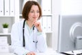 Young brunette female doctor sitting at the table and working at hospital office. Royalty Free Stock Photo