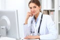 Young brunette female doctor sitting at the table and working at hospital office. Royalty Free Stock Photo