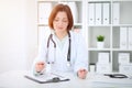 Young brunette female doctor sitting at the table and working at hospital office Royalty Free Stock Photo