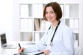 Young brunette female doctor sitting at the table and working at hospital office. Royalty Free Stock Photo