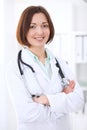 Young brunette female doctor standing with arms crossed and smiling at hospital Royalty Free Stock Photo