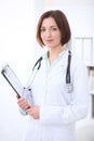 Young brunette female doctor standing with arms crossed and smiling at hospital Royalty Free Stock Photo