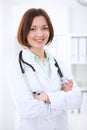 Young brunette female doctor standing with arms crossed and smiling at hospital Royalty Free Stock Photo