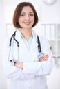 Young brunette female doctor standing with arms crossed and smiling at hospital Royalty Free Stock Photo