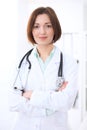 Young brunette female doctor standing with arms crossed and smiling at hospital Royalty Free Stock Photo