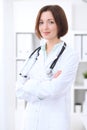 Young brunette female doctor standing with arms crossed and smiling at hospital Royalty Free Stock Photo