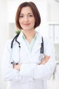 Young brunette female doctor standing with arms crossed and smiling at hospital. Royalty Free Stock Photo