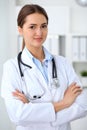 Young brunette female doctor standing with arms crossed and smiling at hospital. Physician ready to examine patient Royalty Free Stock Photo