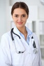 Young brunette female doctor standing with arms crossed and smiling at hospital. Physician ready to examine patient Royalty Free Stock Photo