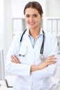 Young brunette female doctor standing with arms crossed and smiling at hospital. Physician ready to examine patient Royalty Free Stock Photo