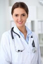 Young brunette female doctor standing with arms crossed and smiling at hospital. Physician ready to examine patient Royalty Free Stock Photo