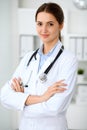 Young brunette female doctor standing with arms crossed and smiling at hospital. Physician ready to examine patient Royalty Free Stock Photo