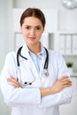 Young brunette female doctor standing with arms crossed and smiling at hospital. Physician ready to examine patient Royalty Free Stock Photo