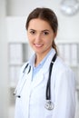 Young brunette female doctor standing with arms crossed and smiling at hospital. Physician ready to examine patient Royalty Free Stock Photo