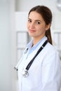 Young brunette female doctor standing with arms crossed and smiling at hospital. Physician ready to examine patient Royalty Free Stock Photo