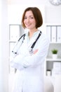 Young brunette female doctor standing with arms crossed and smiling at hospital Royalty Free Stock Photo