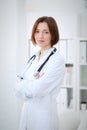 Young brunette female doctor standing with clipboard and smiling in hospital Royalty Free Stock Photo