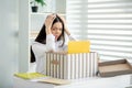 Young brunette female sitting at her desk, holding her head with both hands Royalty Free Stock Photo