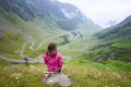 Young female sitting on stone and admiring Transfagarashan road Royalty Free Stock Photo