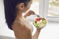 Young brunette fitness woman athete in sportswear standing and eating healthy meal Royalty Free Stock Photo